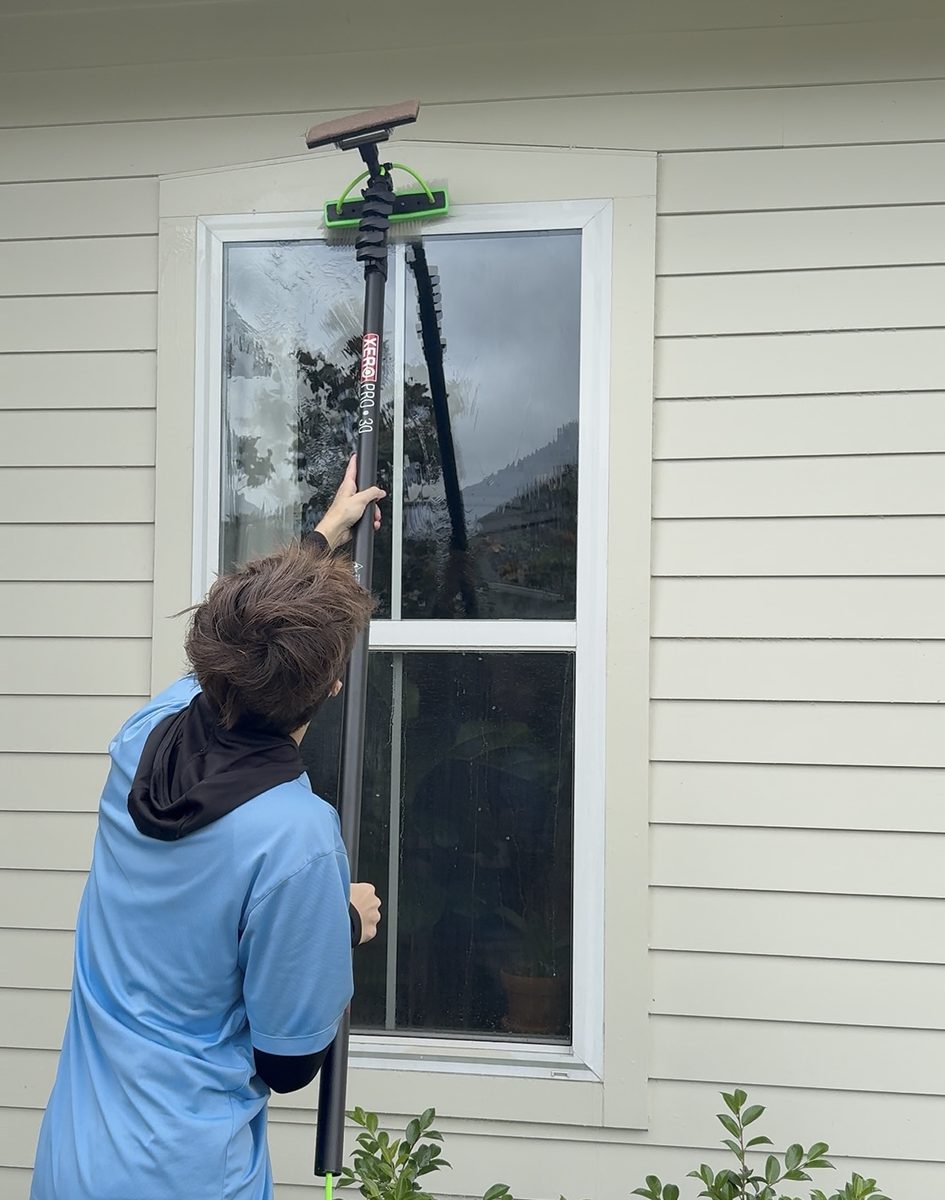 Technician scrubbing exterior window glass with a pure-water fed brush